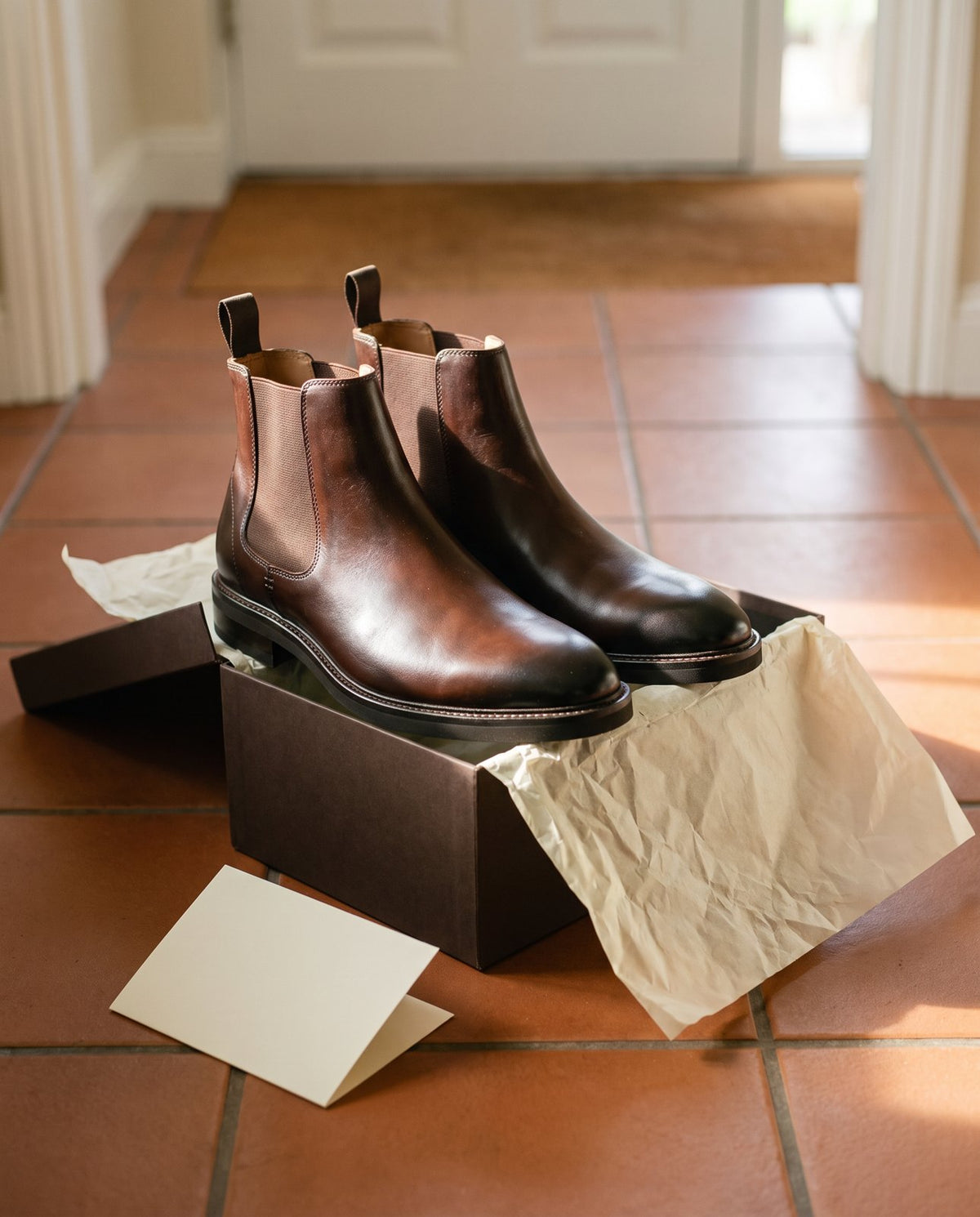 A pair of John White Brecon Chelsea boots in their box on a hallway floor